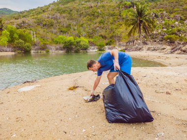 Eldivenli adam denizi kirleten plastik torbalar alıyor. İnsan yapımı kirlilik ve çevresel kirliliğin yol açtığı kumsala çöp dökme sorunu, konsept olarak gönüllü temizleme kampanyası