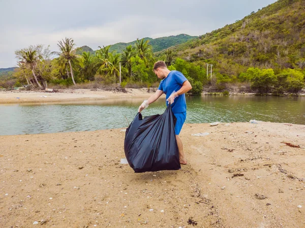 Manusia dalam sarung tangan mengambil kantong plastik yang mencemari laut. Masalah tumpah sampah sampah di pasir pantai disebabkan oleh polusi buatan manusia dan lingkungan, kampanye untuk membersihkan diri secara sukarela dalam konsep — Stok Foto