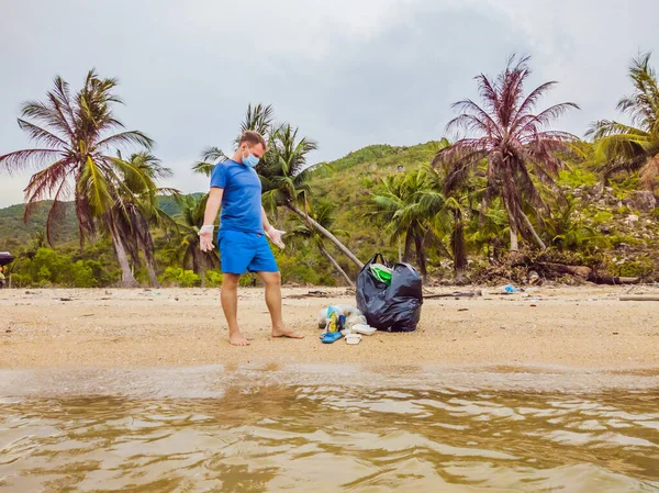 Manusia dalam sarung tangan mengambil kantong plastik yang mencemari laut. Masalah tumpah sampah sampah di pasir pantai disebabkan oleh polusi buatan manusia, kampanye untuk membersihkan diri dalam konsep — Stok Foto