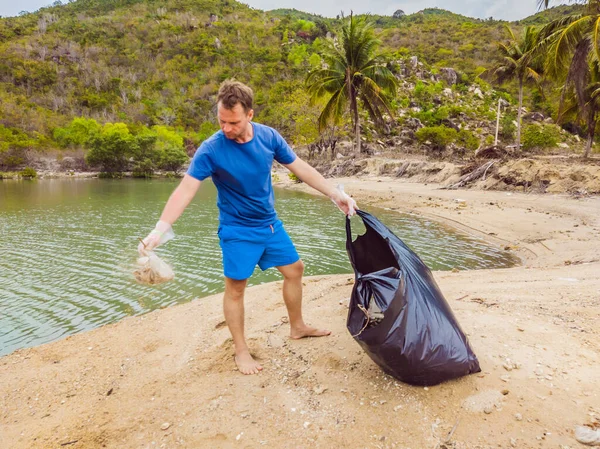 Eldivenli adam denizi kirleten plastik torbalar alıyor. İnsan yapımı kirlilik ve çevresel kirliliğin yol açtığı kumsala çöp dökme sorunu, konsept olarak gönüllü temizleme kampanyası