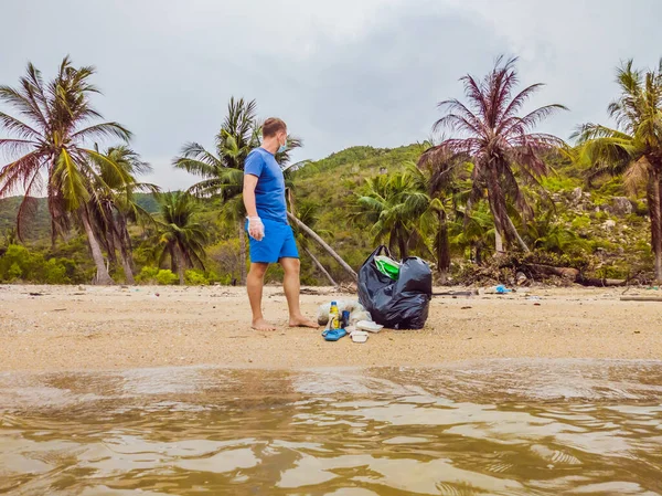 Manusia dalam sarung tangan mengambil kantong plastik yang mencemari laut. Masalah tumpah sampah sampah di pasir pantai disebabkan oleh polusi buatan manusia, kampanye untuk membersihkan diri dalam konsep — Stok Foto