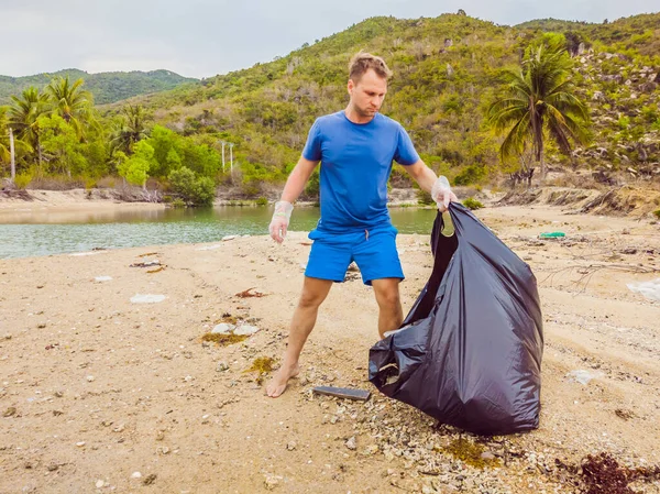 Manusia dalam sarung tangan mengambil kantong plastik yang mencemari laut. Masalah tumpah sampah sampah di pasir pantai disebabkan oleh polusi buatan manusia dan lingkungan, kampanye untuk membersihkan diri secara sukarela dalam konsep — Stok Foto