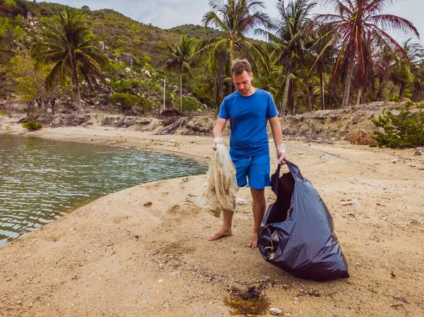 Manusia dalam sarung tangan mengambil kantong plastik yang mencemari laut. Masalah tumpah sampah sampah di pasir pantai disebabkan oleh polusi buatan manusia dan lingkungan, kampanye untuk membersihkan diri secara sukarela dalam konsep — Stok Foto