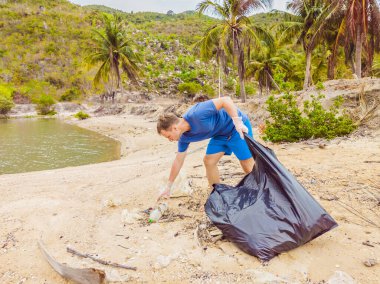 Eldivenli adam denizi kirleten plastik torbalar alıyor. İnsan yapımı kirlilik ve çevresel kirliliğin yol açtığı kumsala çöp dökme sorunu, konsept olarak gönüllü temizleme kampanyası