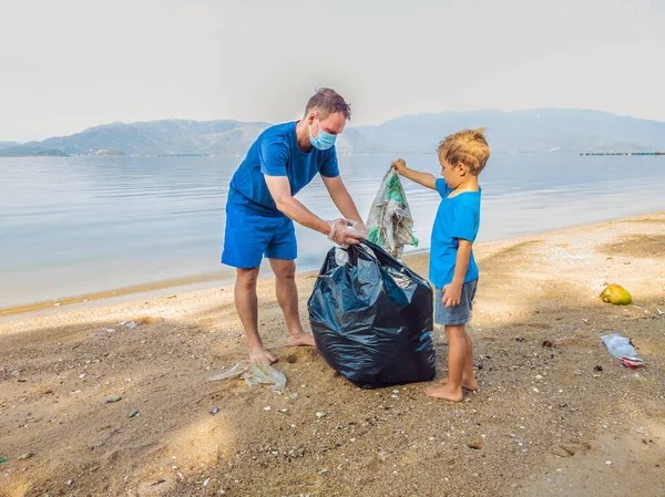 Junge glückliche Familienaktivisten sammeln Plastikmüll am Strand. Papa und Sohn räumen freiwillig Müll weg. Probleme mit der Umweltverschmutzung. Freizeit im Freien. Natürliche Erziehung der Kinder — Stockfoto