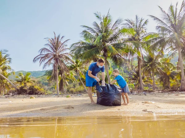 Aktivis keluarga muda yang bahagia mengumpulkan sampah plastik di pantai. Ayah dan anak sukarela membersihkan sampah. Masalah polusi lingkungan. Rekreasi gaya hidup luar ruangan. Pendidikan alami anak-anak — Stok Foto