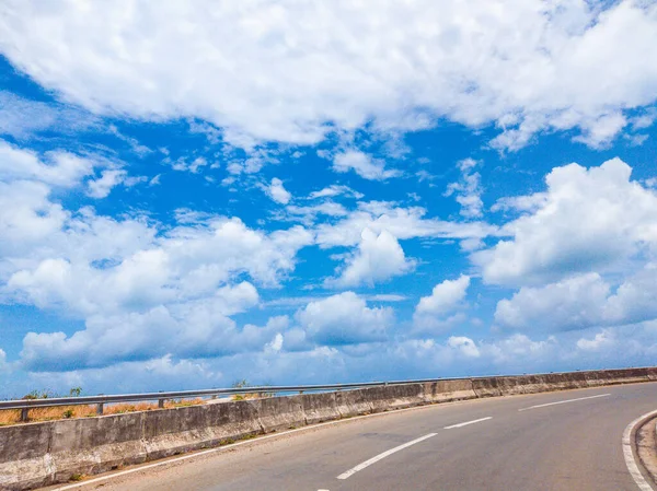 Krásný výhled na suchý asfaltový prázdný automobil křivolaká silnice s vyznačovací čáry za slunečného letního dne s modrou oblačnou oblohou. Cesta autem koncepce pozadí — Stock fotografie