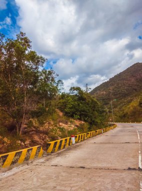 Kuru asfalt boş otomobil yolu beton bariyer ve işaretli çizgiler güneşli bir yaz gününde mavi bulutlu gökyüzü. Araba yolculuğu konsepti
