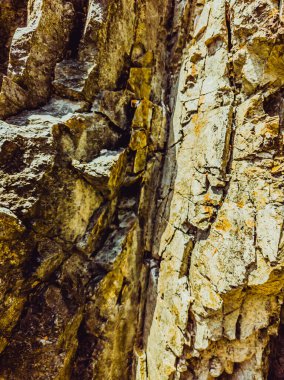 Doğal arka plan. Yakın kenarlı, eski püskü uçurum çatlakları. Dağların gri-kahverengi kaya dokusu. Renkli fotoğrafta eski ve soluk Matt tarzı renkler. Geolog, dağcılık ya da sıkı çalışma kavramı