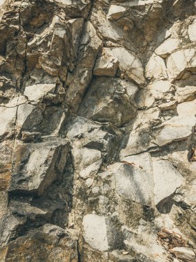 Doğal arka plan. Yakın kenarlı, eski püskü uçurum çatlakları. Dağların gri-kahverengi kaya dokusu. Renkli fotoğrafta eski ve soluk Matt tarzı renkler. Geolog, dağcılık ya da sıkı çalışma kavramı