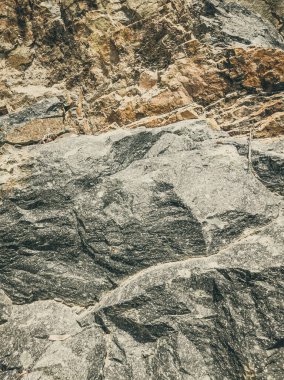 Doğal arka plan. Yakın kenarlı, eski püskü uçurum çatlakları. Dağların gri-kahverengi kaya dokusu. Renkli fotoğrafta eski ve soluk Matt tarzı renkler. Geolog, dağcılık ya da sıkı çalışma kavramı