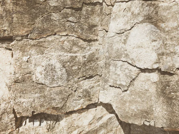 Natuurlijke achtergrond. Nauwkeurige scheuren in de rotswand. Grijs-bruine stenen rotsstructuur van bergen. Vintage en vervaagde matte stijl kleur in getinte foto. Begrip geolog, bergbeklimmen of hard werken — Stockfoto