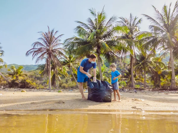Aktivis keluarga muda yang bahagia mengumpulkan sampah plastik di pantai. Ayah dan anak sukarela membersihkan sampah. Masalah polusi lingkungan. Rekreasi gaya hidup luar ruangan. Pendidikan alami anak-anak — Stok Foto
