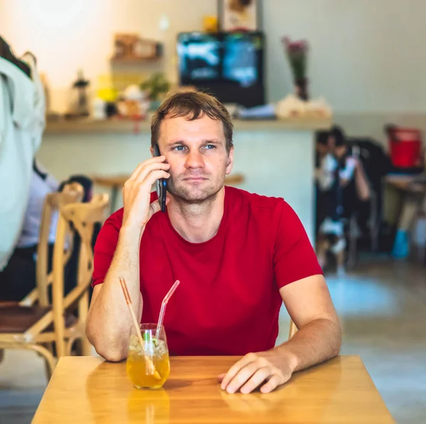 Kısıtlanmış gülümseme mutlu genç adam kafede kırmızı gömlekli akıllı telefona cevap verir, buzlu çay içer, birini bekler ya da iş birliği yapar. Gerçek insanlar ifade eder, hayat sorunları çözer, iletişim kurar, ilişki kurar