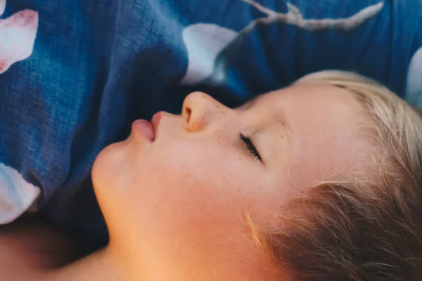 Aranyos kisfiú édesen alszik a párnán, fényes reggeli napsugarakkal az ablakból, szundikál. Boldog lefekvést a gyerekeknek. Korai ébredés, késői elalvás, egészséges alvás bioritmusa — Stock Fotó