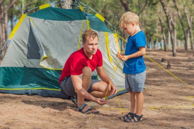 Kamp yapan turistler, yaz ormanlarında Lazur Denizi yakınlarında yeşil gri kamp alanlarını kuruyorlar. Tatlı çocuk babasının çadır kurmasına yardım ediyor. Çocukların doğal eğitimi