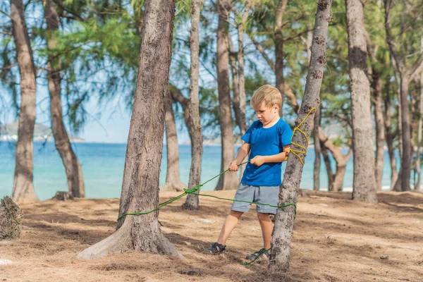 Telttailu ihmiset ulkona elämäntapa turisteja kesällä metsässä lähellä Lazur merelle. Vaalea poika sinisessä t-paidassa opiskelee selviytymistekniikoita, harjoittelee köysisolmujen sitomista. Luonnolliset lapset koulutus — kuvapankkivalokuva
