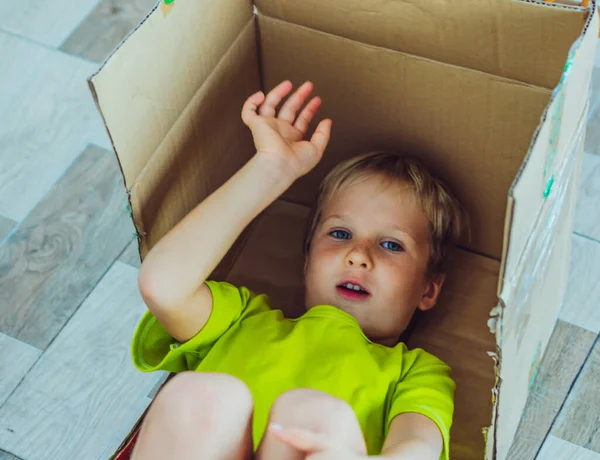 Mischievous boy play hiding in box because does not want to go to school or kindergarten on the first day of school in September. Childhood problems behaviour education psychology, family relationship