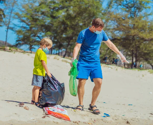 Volunteer wajah biru masker hutan pasir pantai. Anak membantu ayah memegang tas hitam untuk mengambil sampah. Masalah tumpah sampah sampah planet polusi perlindungan lingkungan. Pendidikan anak alami — Stok Foto