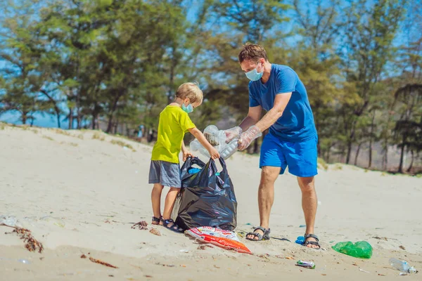 Volunteer wajah biru masker hutan pasir pantai. Anak membantu ayah memegang tas hitam untuk mengambil sampah. Masalah tumpah sampah sampah planet polusi perlindungan lingkungan. Pendidikan anak alami — Stok Foto