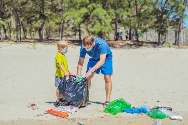 Volunteer blue face mask forest sand beach. Son helps father hold black bag for pick up garbage. Problem spilled rubbish trash planet pollution environmental protection. Natural children education