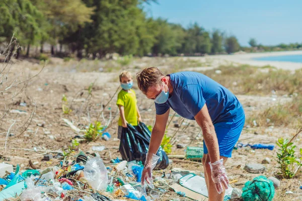 Volunteer wajah biru masker hutan pasir pantai. Anak membantu ayah memegang tas hitam untuk mengambil sampah. Masalah tumpah sampah sampah planet polusi perlindungan lingkungan. Pendidikan anak alami — Stok Foto