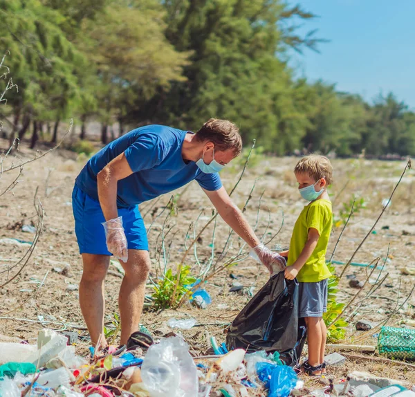 Volunteer wajah biru masker hutan pasir pantai. Anak membantu ayah memegang tas hitam untuk mengambil sampah. Masalah tumpah sampah sampah planet polusi perlindungan lingkungan. Pendidikan anak alami — Stok Foto