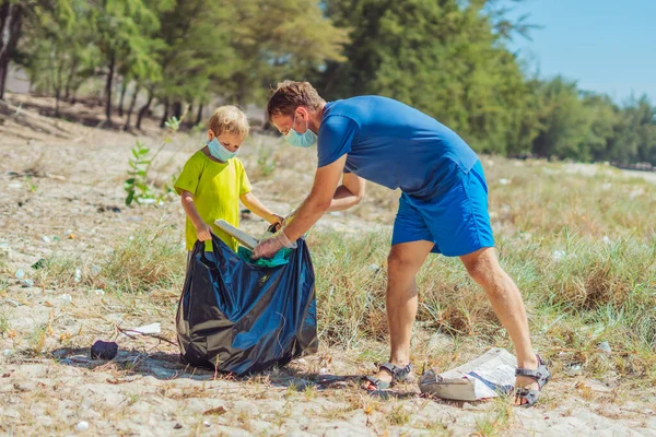 Volunteer wajah biru masker hutan pasir pantai. Anak membantu ayah memegang tas hitam untuk mengambil sampah. Masalah tumpah sampah sampah planet polusi perlindungan lingkungan. Pendidikan anak alami — Stok Foto