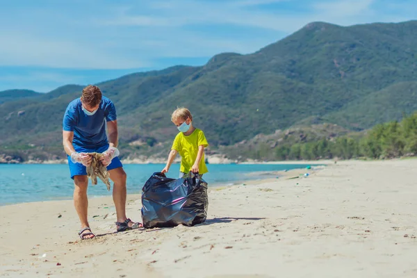 Relawan topeng wajah biru pantai surga pasir lazur laut. Ayah mengambil sampah ke dalam tas hitam. Masalah tumpah sampah sampah planet polusi perlindungan lingkungan. Pendidikan anak alami — Stok Foto