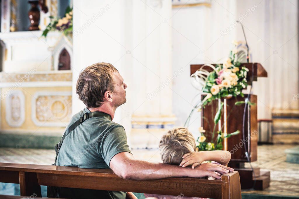Christian dad tells his son Bible stories about Jesus sitting in kirk. Faith, religious education, modern church, father day, fatherly responsibilities, father influence on formation of son worldview