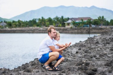 Baba çömelmiş, kucaklaşan oğul, göl kenarında el ele tutuşup uzaklara bakıyor. Mutlu çocukluk, babalık. Aile birlikte yürür. Evde doğal eğitim, babaların günlük sorumlulukları etkili.