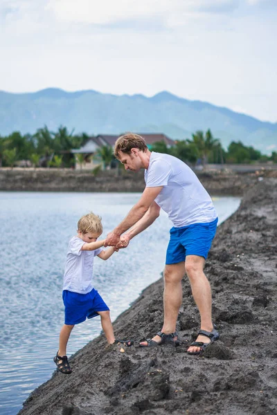 Dad helps son go down to lake water, explains safety rules. Family together walk play. Home natural child education, fathers day, fatherly responsibilities, influence on formation of son worldview — Stock Photo, Image