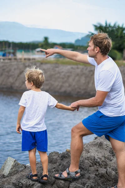 Father and son walk along man made breeding fish lake mountain background. Happy childhood. Home natural child education, fathers day, dad responsibilities, influence on son worldview formation — Stock Photo, Image