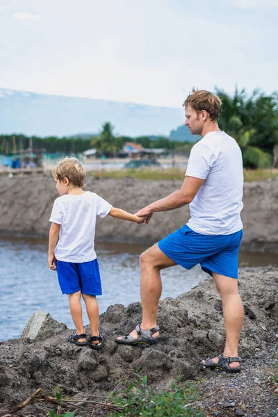 Father and son walk along man made breeding fish lake mountain background. Happy childhood. Home natural child education, fathers day, dad responsibilities, influence on son worldview formation — Stock Photo, Image