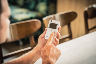 Genç ciddi erkek doktor alternatif tıp olarak biyolojik rezonans tedavisini kullanmayı düşünüyor, küçük taşınabilir yaşam dengesi cihazına bakarak solucan istilasını tedavi etmek için