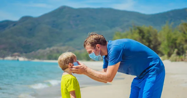 Keselamatan era realitas normal baru selama pandemi global COVID 19. Ayah menemani anak memakai topeng melindungi dan mencegah coronavirus bahkan berjalan di pantai laut pasir alam dekat taman hutan pada hari yang cerah — Stok Foto