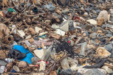Deniz kıyısındaki taşlara dökülen çöpler gri çakıllar. Kullanılmış kirli plastik şişeler. Çevre kirliliği, ekolojik sorun. Soyut Bileşik Doku Özellikli Web Tasarımı