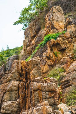 Parlak turuncu, parlak, kahverengi, sarı taştan, döküntü kayalık uçurum, doku dağlarını çatlatıyor. Jeoloji kavramı, doğadaki güzellik gücü. Doğal yaz kompozisyonu arkaplan tasarımı