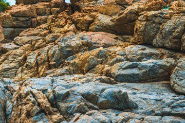 Parlak turuncu, parlak, kahverengi, sarı taştan, döküntü kayalık uçurum, doku dağlarını çatlatıyor. Jeoloji kavramı, doğadaki güzellik gücü. Doğal yaz kompozisyonu arkaplan tasarımı