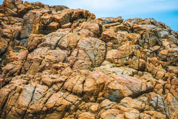Dari dekat terlihat batu kuning coklat cerah berwarna jingga yang lusuh tebing retak tekstur pegunungan. Konsep geologi, kekuatan kecantikan di alam. Desain latar belakang komposisi musim panas alami — Stok Foto