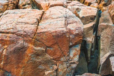 Parlak turuncu, parlak, kahverengi, sarı taştan, döküntü kayalık uçurum, doku dağlarını çatlatıyor. Jeoloji kavramı, doğadaki güzellik gücü. Doğal yaz kompozisyonu arkaplan tasarımı