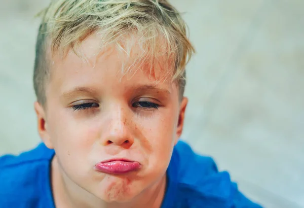 Close-up portret jongen ondeugend schattig blond sluiten blauwe ogen, stak uit lip gebaar van onwil, sproeten gezicht spelen in de stemming. Grappige foto, gelukslevensstijl. Kinderopvang, kindertijd, gedrag — Stockfoto