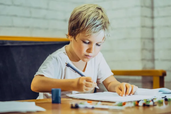 stock image Portrait blond cute Preschool boy holding pen notebook look serious hard diligently diligently learn write, facial expressions gestures. Children behaviour education problems, home school concept