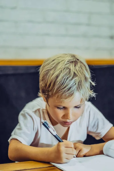 पोर्ट्रेट गोरा गोंडस प्रीस्कूल मुलगा धारण पेन नोटबुक गंभीरपणे कठोर परिश्रमपूर्वक लेखन, चेहर्यावरील अभिव्यक्ती इशारा शिकणे. मुलांचे वर्तन शिक्षण समस्या, घर शाळा संकल्पना — स्टॉक फोटो, इमेज