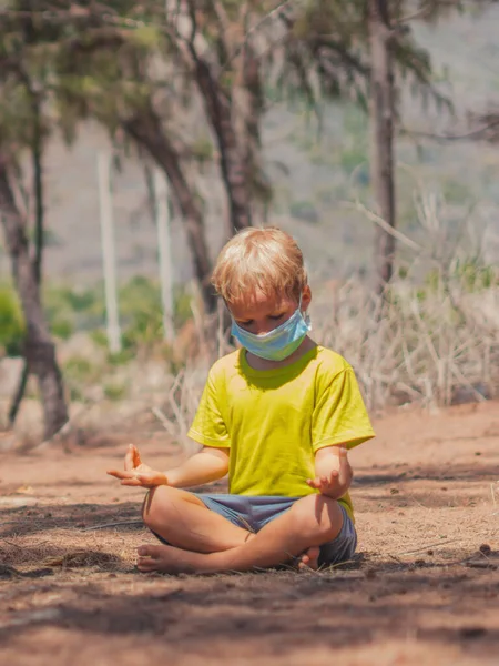 Pria kecil yang tenang duduk bermeditasi berlatih hutan yoga taman udara segar, memakai COVID virus wajah pelindung topeng. Anak-anak muda beristirahat meredakan emosi negatif menutup mata teratai menimbulkan kesadaran — Stok Foto