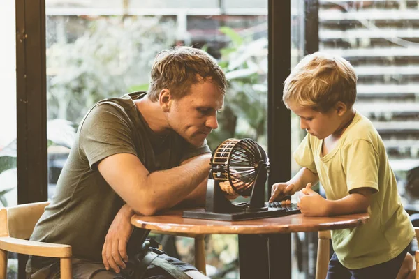 Father blond son boy play lotto, round sphere spins with small orange balls numbers written, table loto game. Children home education learn numeros find common language develop logical thinking — Stock Photo, Image