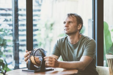 Genç ciddi düşünceli adam loto topunu yuvarlak tutuyor küçük toplar çeviriyor, masa loto oyunu gelecekteki sorunun sembolü, yaşam krizi, seçim sorumluluğu. Uzaktaki pencereye bak yüz ifadesi jesti