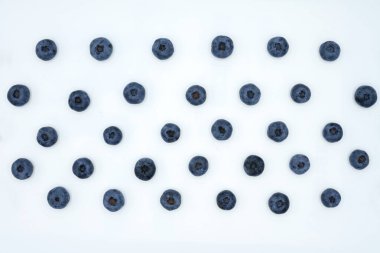 Beyaz bir zemin üzerinde olgun sulu yaban mersinlerinin paralel sıraları