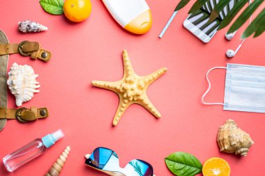 Pembe arka planda deniz yıldızı etrafında plaj tatili için aksesuarlar. Bir salgın sırasında denize seyahat ve tatil kavramı. Üst görünüm