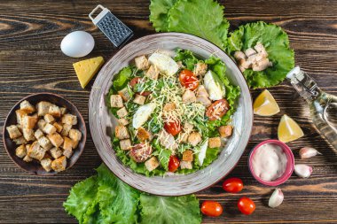 Tahta bir masada iştah açıcı taze Sezar salatası ve onu pişirmek için malzemeler. Üst görünüm